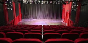 Image shows The Playhouse theatre space with red chairs and stage