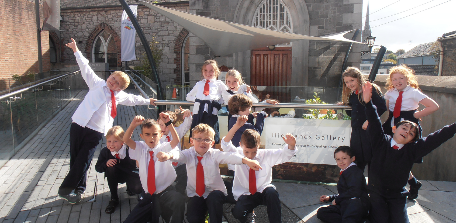 A group of primary school children smiling and posing outside Highlanes arts centre