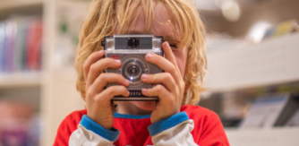 Photo of little boy holding camera in front of his face.