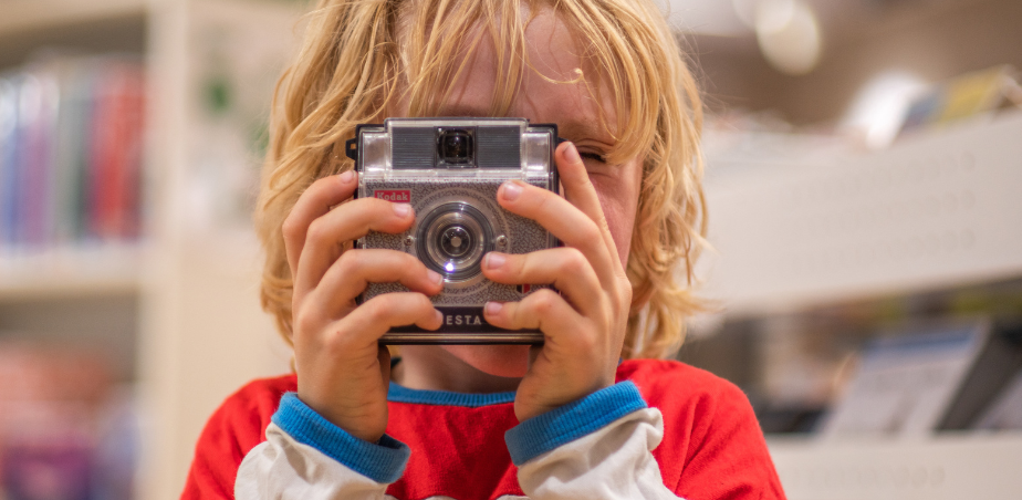 Photo of little boy holding camera in front of his face.