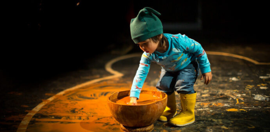 Small child with hand in bowl of paint