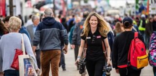 A woman with a camera walks through a busy pedestrian street.