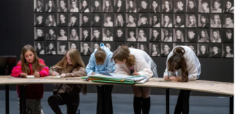 Children at desk in front of wall at portraits