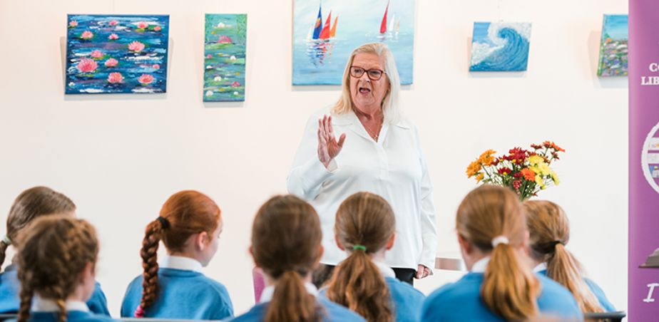 Image shows an artist talking to a group of school students.