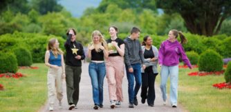 A group of smiling students walking up a garden path.