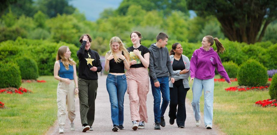 A group of smiling students walking up a garden path.