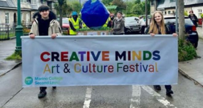 Marino College Student Ambassadors lead a parade with a banner which reads Creative Minds Arts & Culture Festival