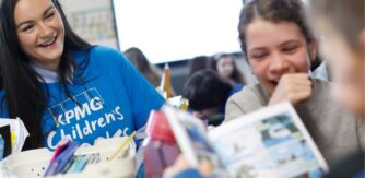 Children laugh together while reading a book with Children's Books Ireland volunteer