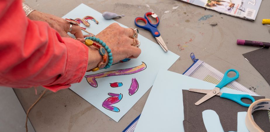 A persons arm with colourful bracelets creates a drawing on a sheet.