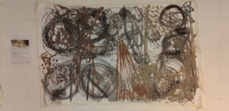 A large drawing with swirls in black, brown and amber taped to a white wall.