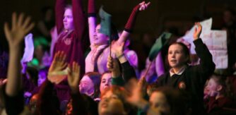 An audience of young people with raised hands and banners at a film awards event