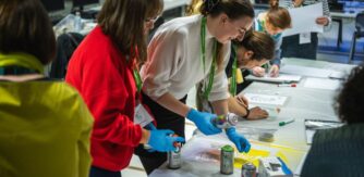 People spray paint on white paper for National Day 2024 creative workshop with Street Ink