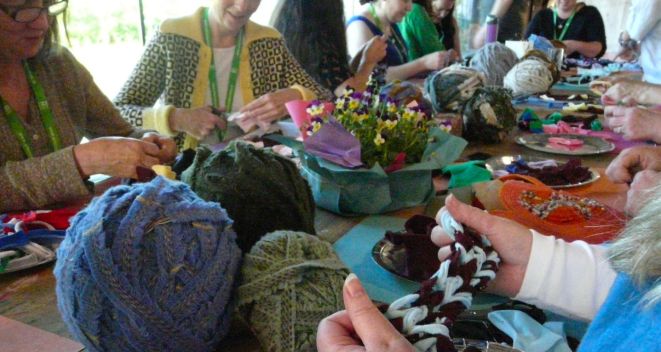 Participants at a Circular Fashion creative workshop sit at a table of colourful fabric and wool for Portal Regional Day 2025