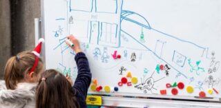 School children draw on a whiteboard for Creative Schools