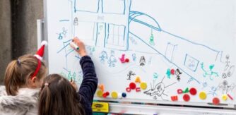 School children draw on a whiteboard for Creative Schools