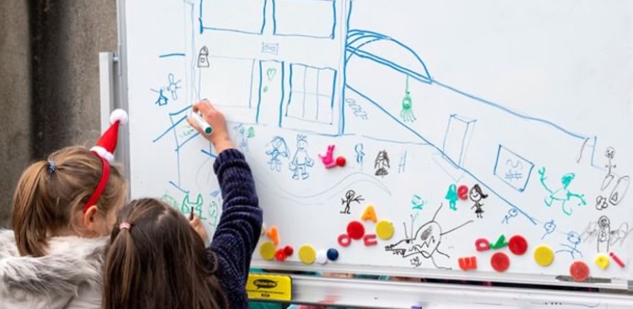 School children draw on a whiteboard for Creative Schools