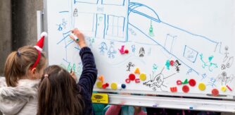 School children draw on a whiteboard for Creative Schools