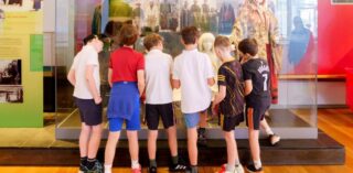 School tour gather around an exhibition at National Museum in Mayo