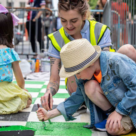 Kathi Burke, artist and children painting on the tarmac during the install of Open Road on Oliver Plunkett Street, Cork city. Photo credit: Clare Keogh